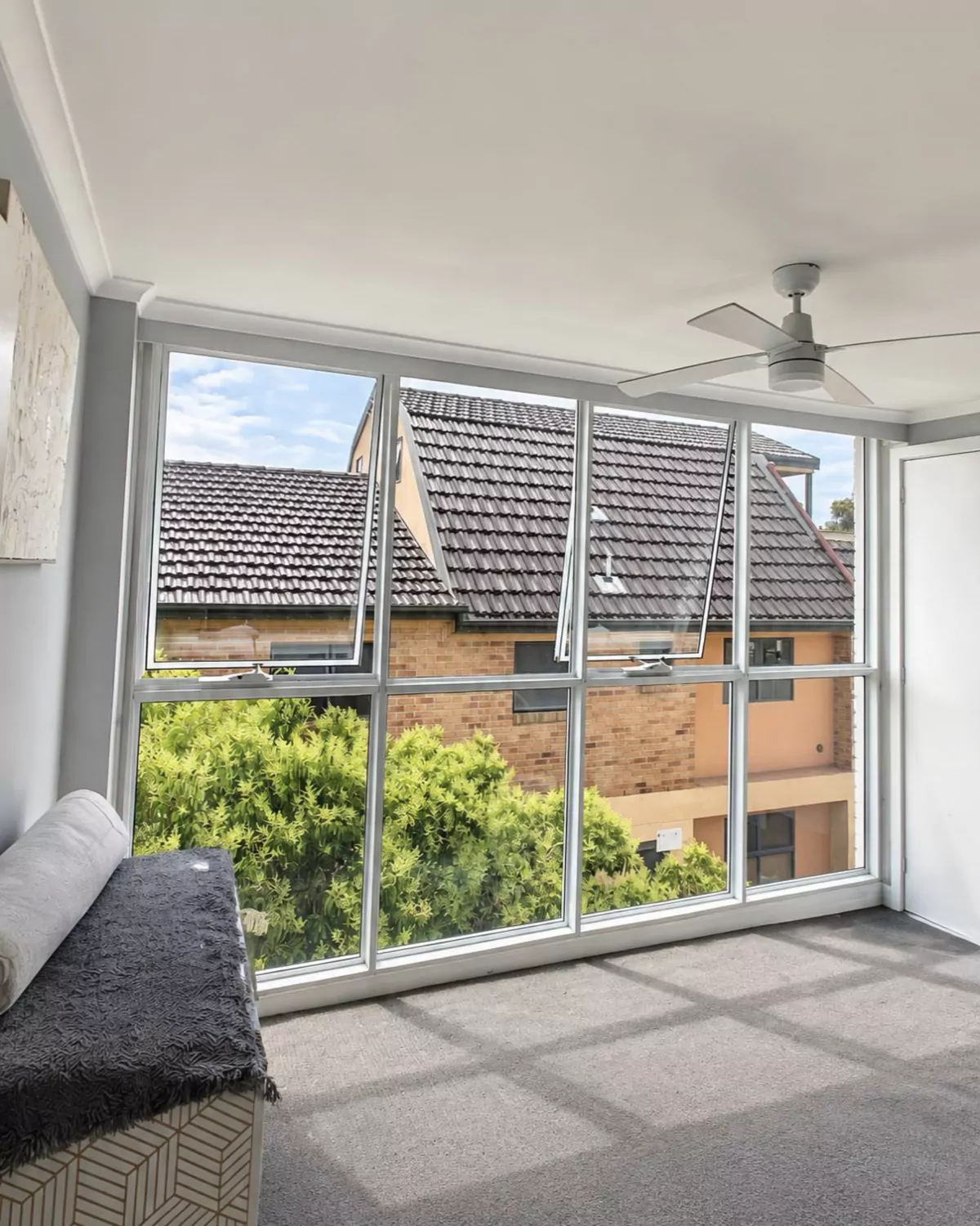 The finished room: a wall of white aluminium-framed glass with two awning windows open