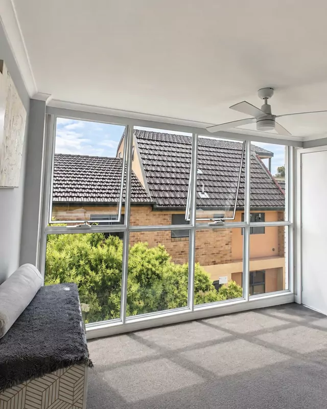 The finished room: a wall of white aluminium-framed glass with two awning windows open