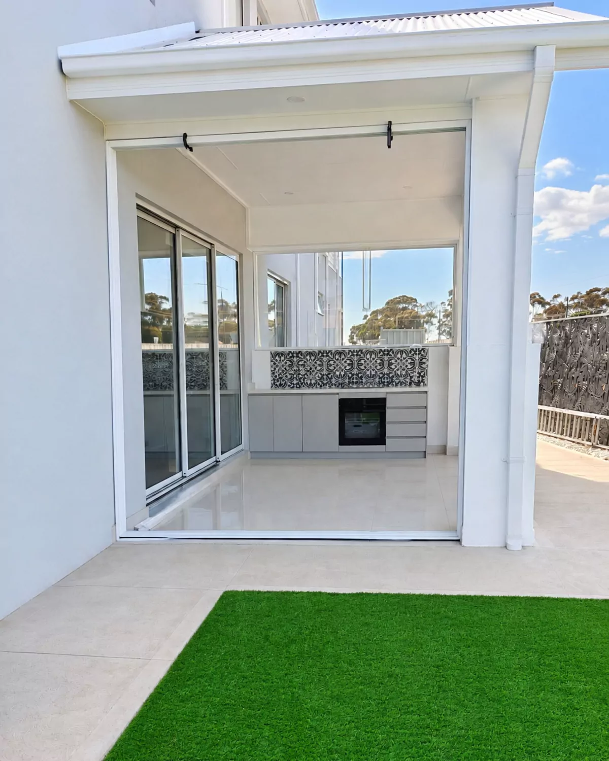 The finished white-framed alfresco enclosure seen from the lawn on a sunny day