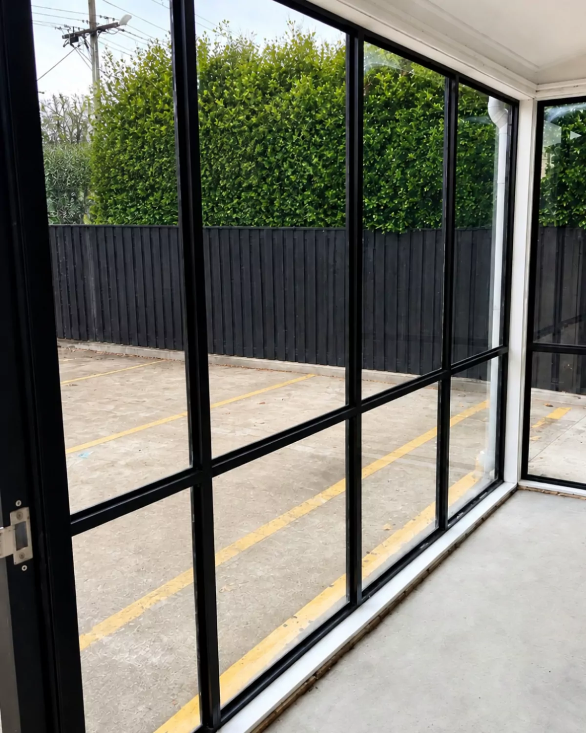 The finished glass wall from inside: straight black frames and clear new glass