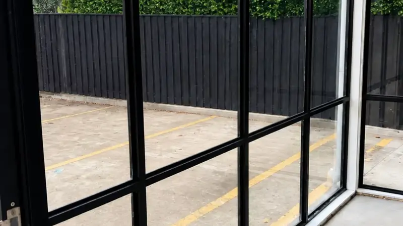 The finished glass wall in a black aluminium frame, looking out to a car park.