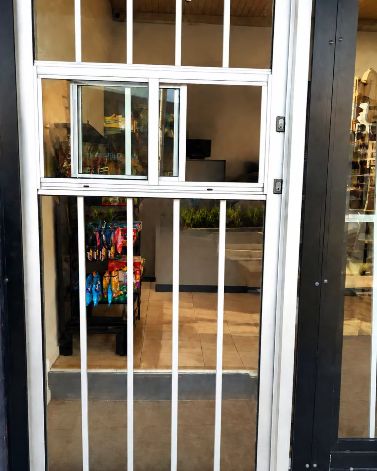 Close-up of the new white entry door with vertical security bars and a small sliding window