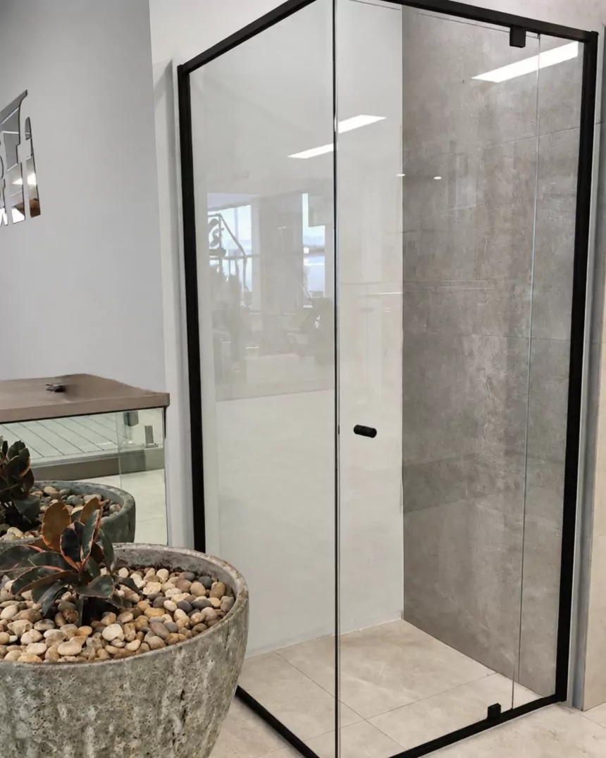 After: a clear glass shower screen with a slim black frame and a pivot door in the same corner